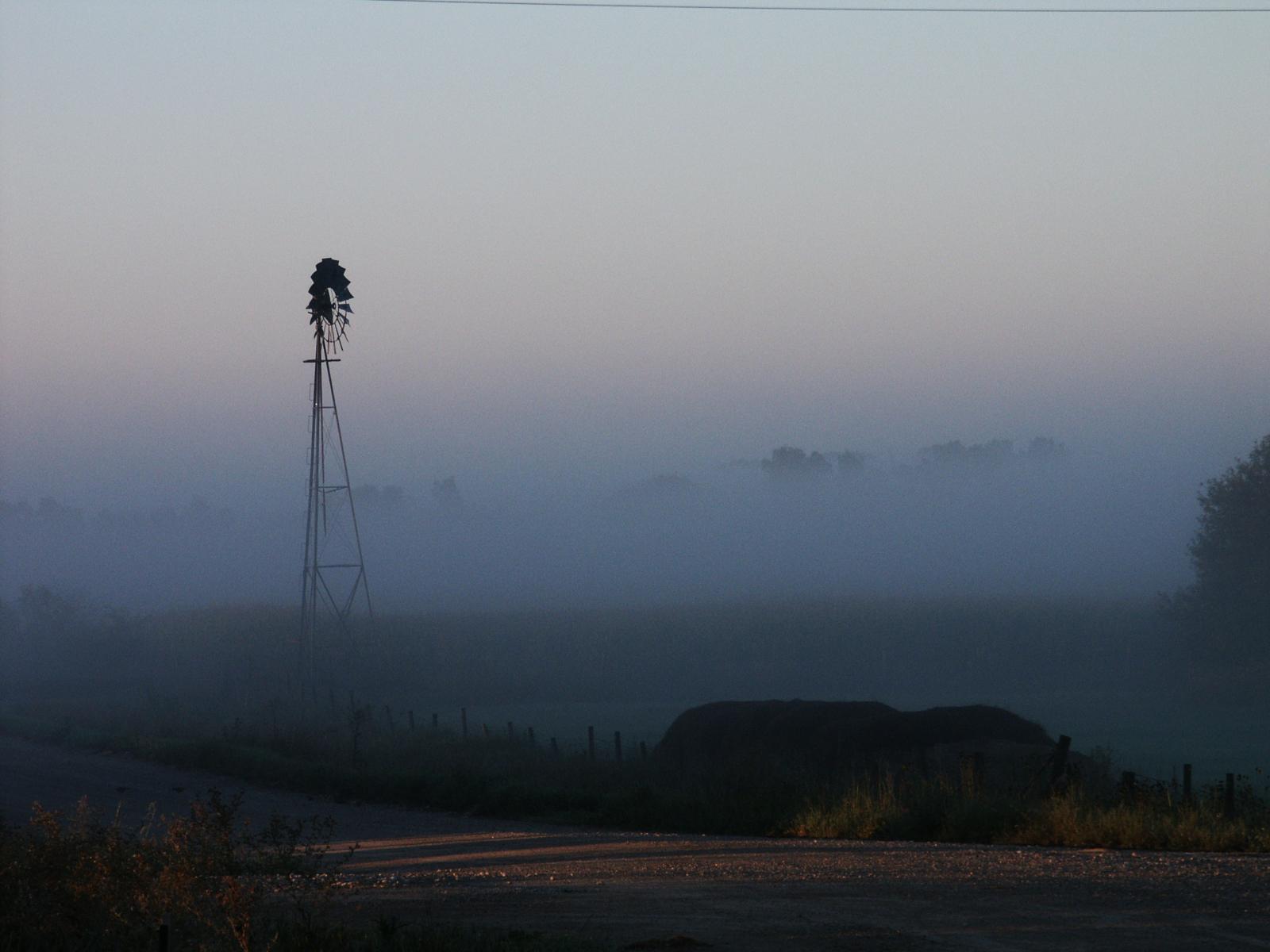 Windmill shrouded in fog at a farm outside of Walker, Iowa